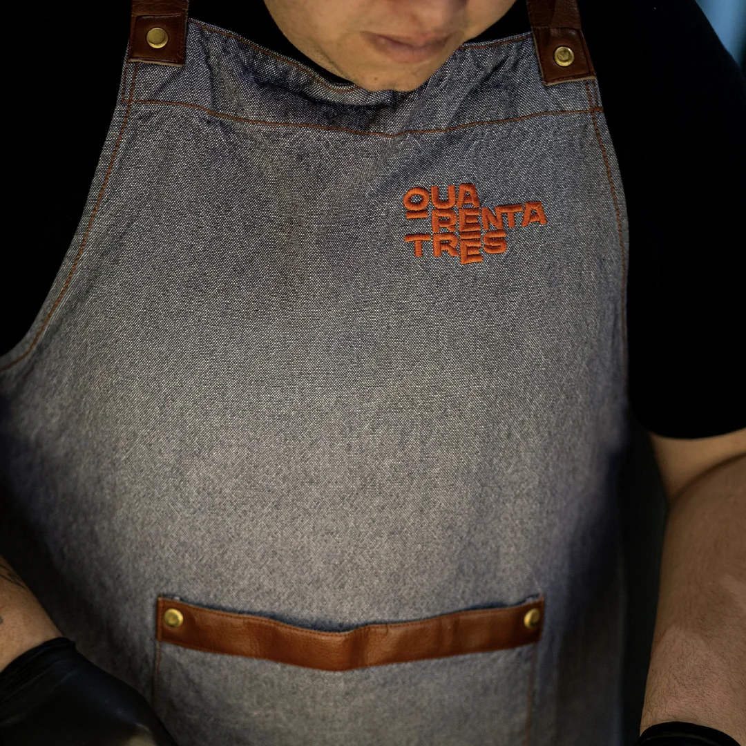 Projeto Quarenta e três da Nhdesign: Detalhe de uniforme em cinza com logótipo Quarenta e Três bordado em vermelho