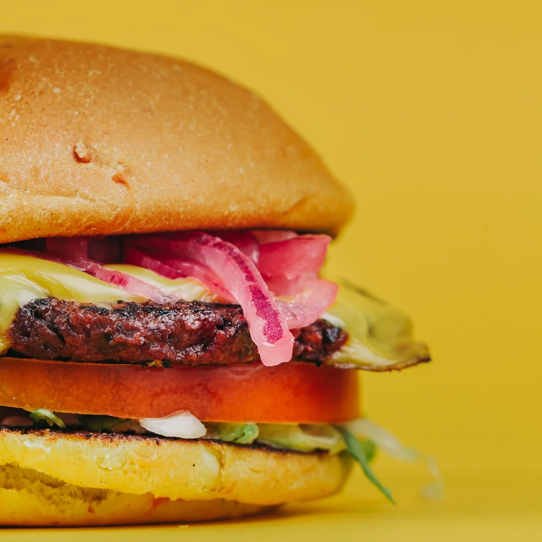 Projeto SMASH VS THREAT da Nhdesign: Hambúrguer Sneaky Smash com carne, cebola roxa e molho em fundo laranja