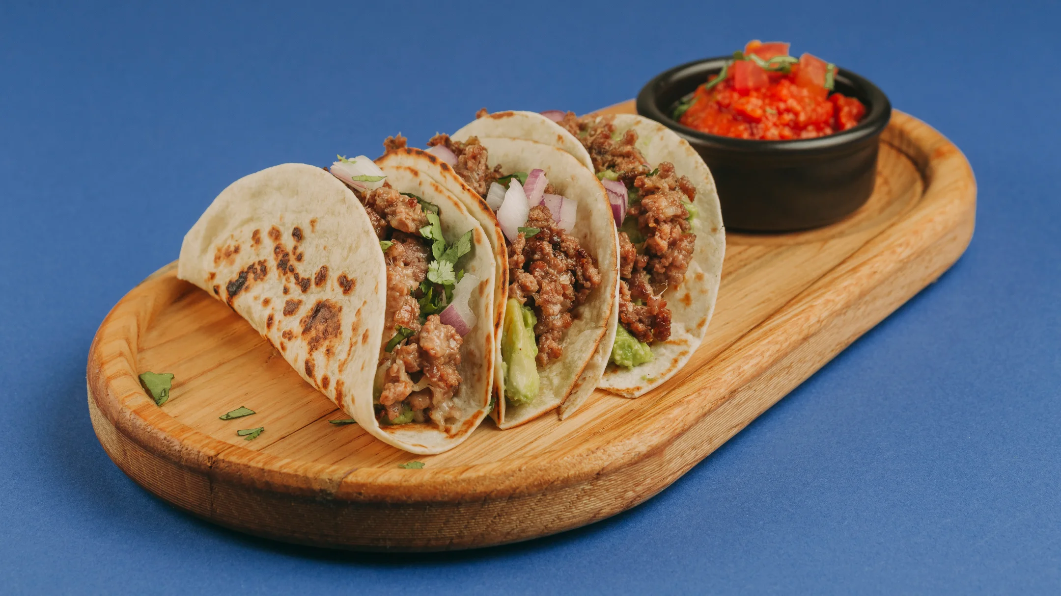 Projeto SMASH VS THREAT da Nhdesign: Conjunto de tacos em prato de madeira servidos com molho picante vermelho