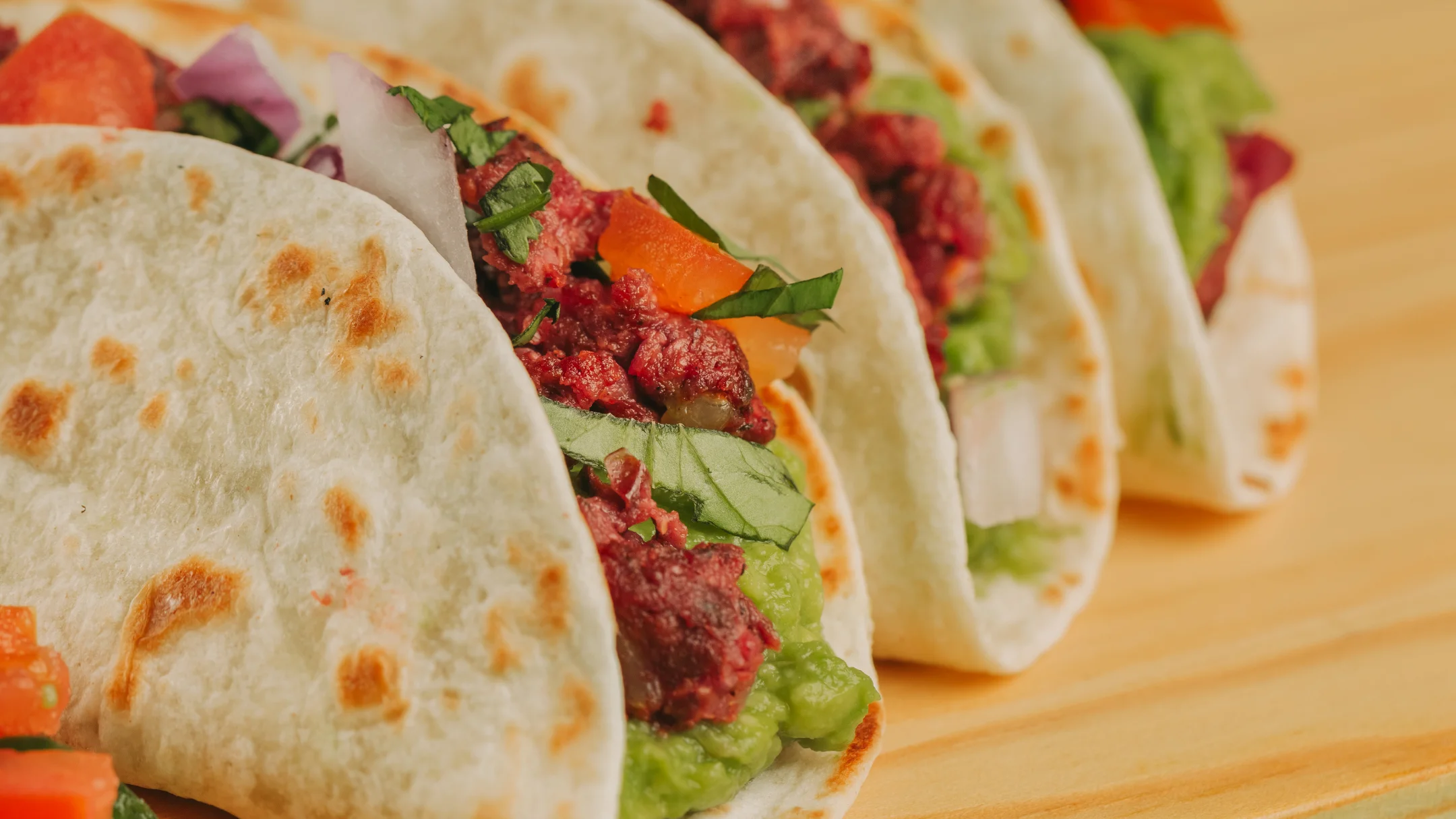 Projeto SMASH VS THREAT da Nhdesign: Tacos recheados com carne e vegetais servidos em fundo claro