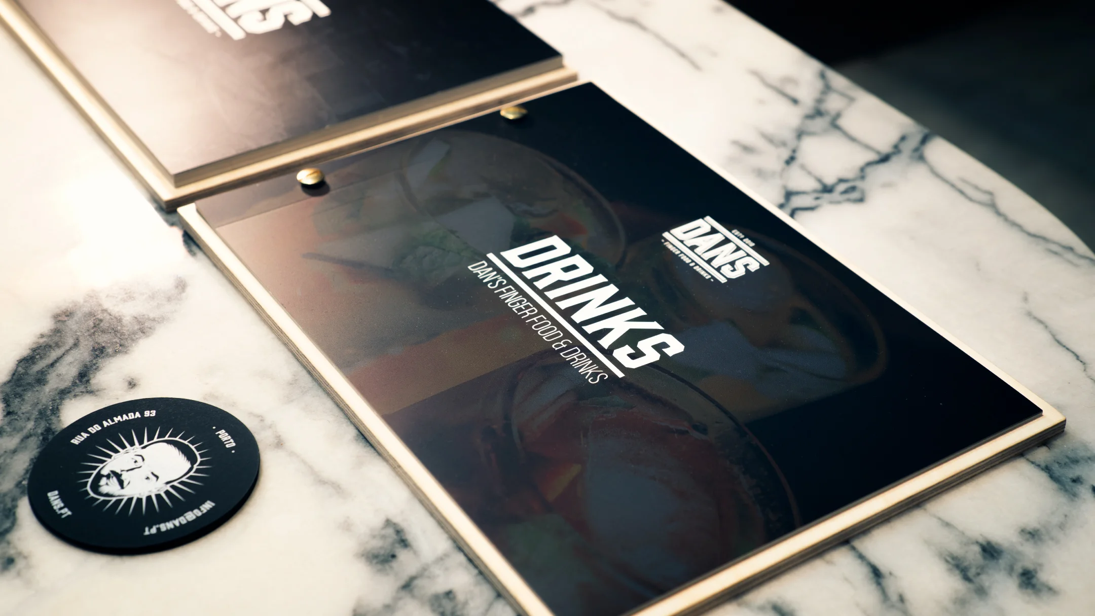 Projeto DANS da Nhdesign: Menu impresso DANS em fundo de mármore com talheres