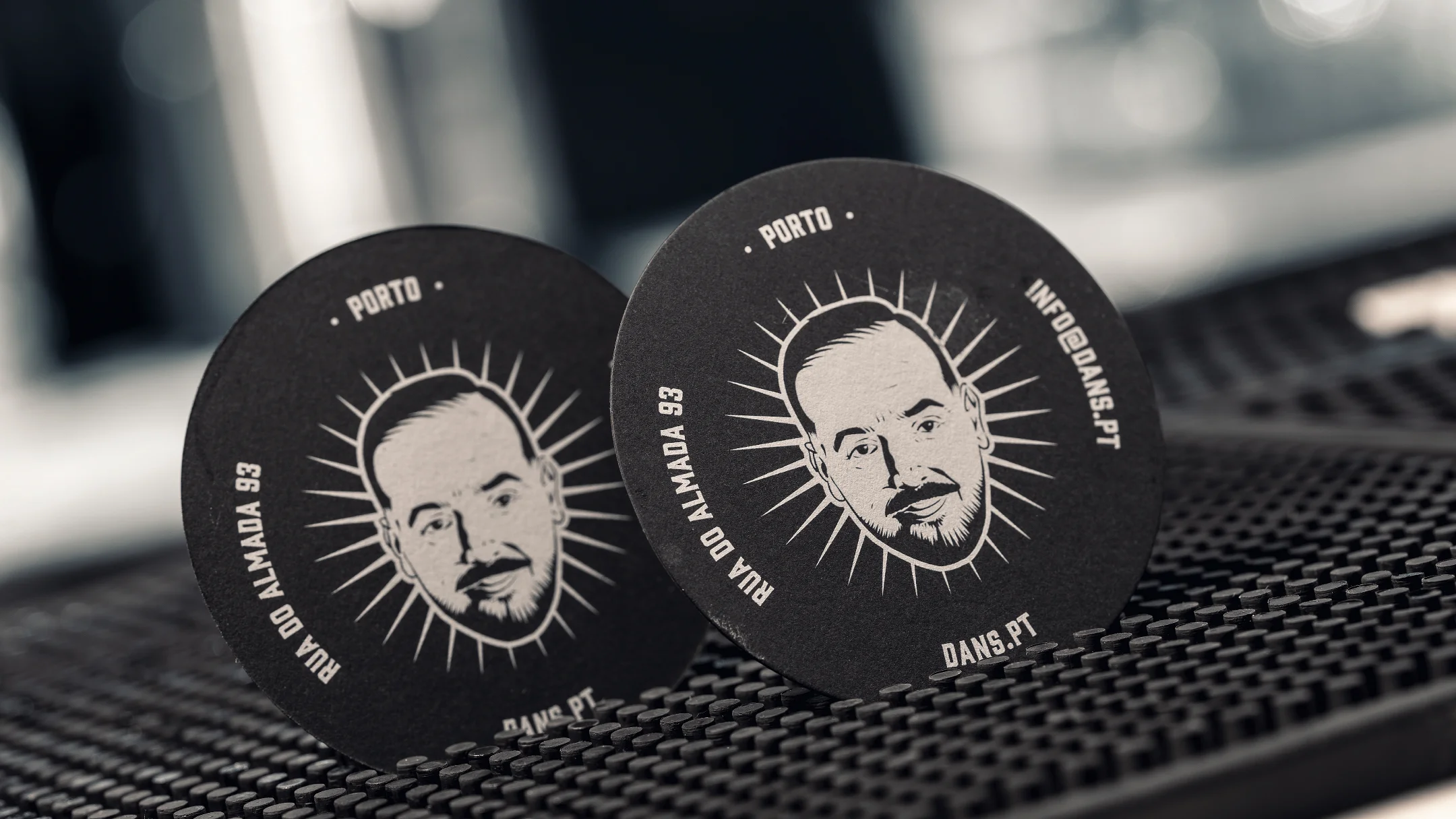 Projeto DANS da Nhdesign: Porta-copos pretos do DANS com logótipo em branco no balcão do bar