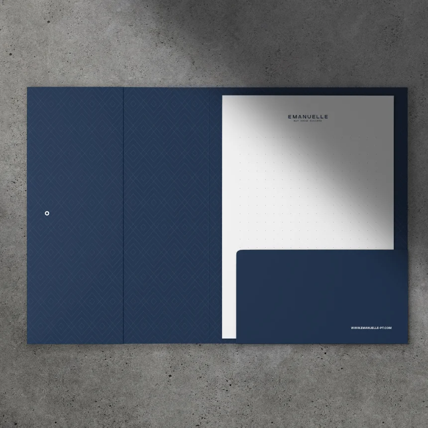 Projeto Emanuelle da Nhdesign: Capa da Emanuelle aberta com folha de carta dentro, sobre fundo de cimento.