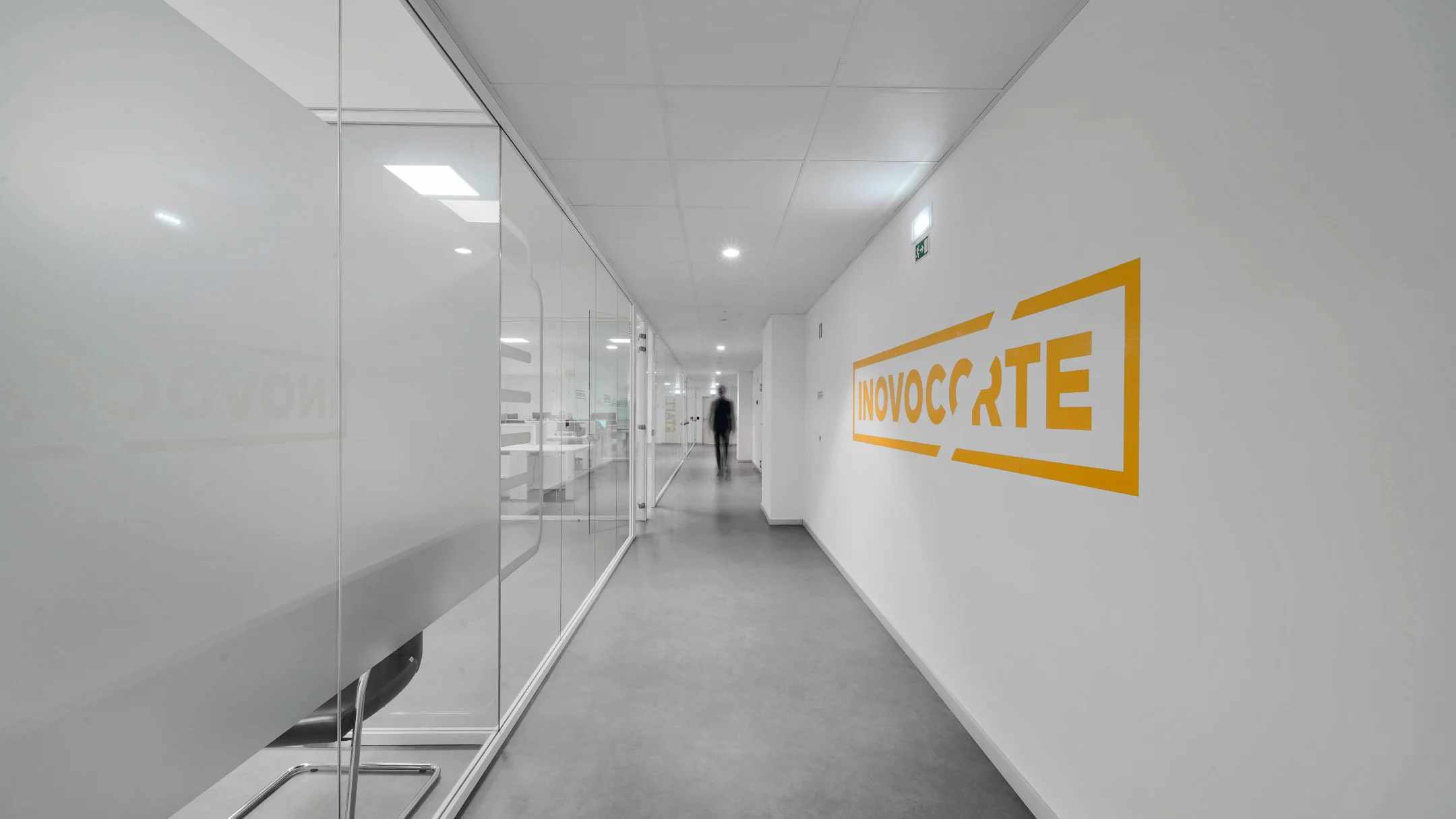 Projeto Inovocorte da Nhdesign: Corredor branco das instalações da Inovocorte com letreiro amarelo na parede