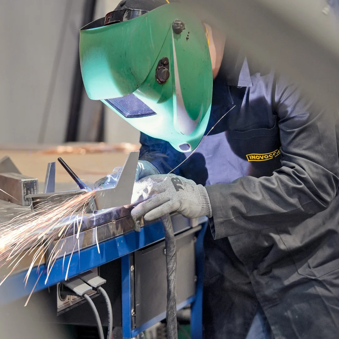 Projeto Inovocorte da Nhdesign: Operário da Inovocorte com máscara a soldar peças metálicas em ambiente fabril