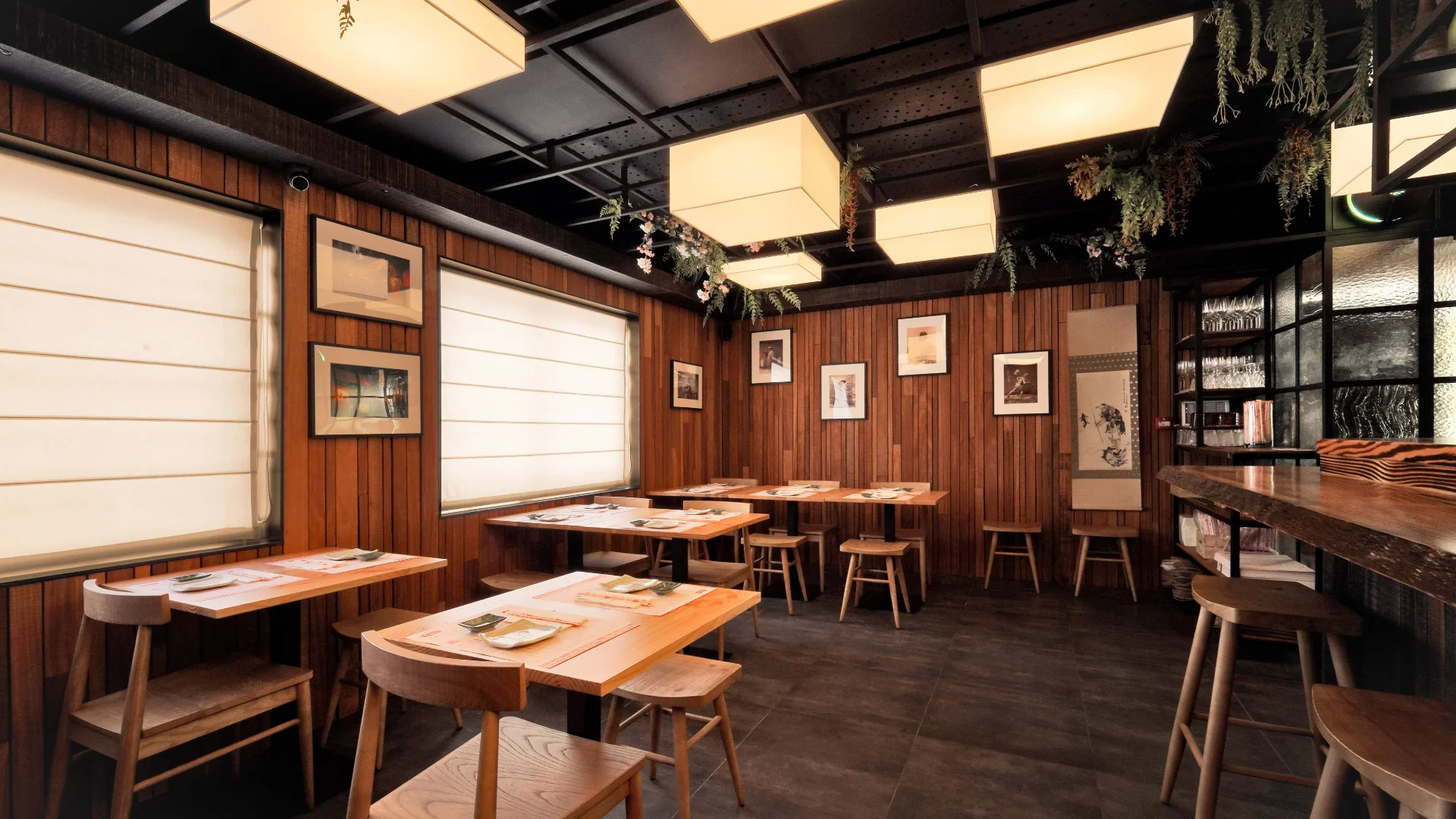 Projeto Izakaya Matsuri da Nhdesign: Fotografia do interior de um restaurante com paredes e mesas de madeira.