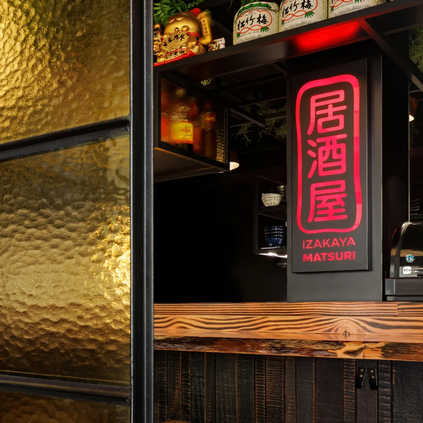 Projeto Izakaya Matsuri da Nhdesign: Um letreiro luminoso com o logótipo no balcão de um bar.