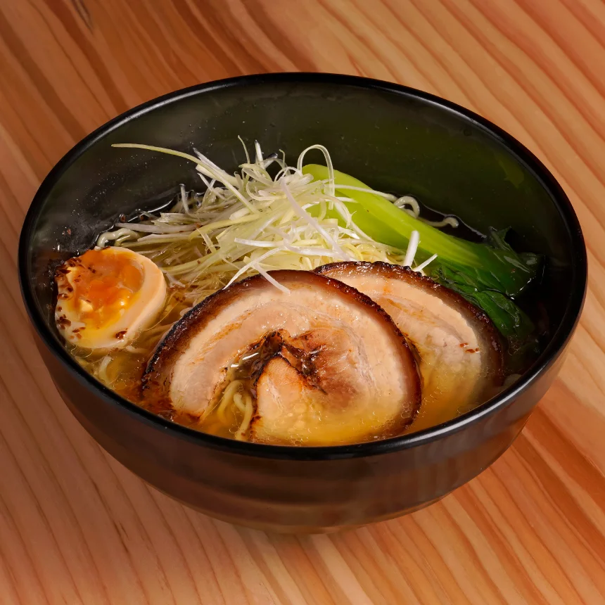 Projeto Izakaya Matsuri da Nhdesign: Uma tigela de ramen com carne e vegetais misturados sobre uma mesa de madeira.