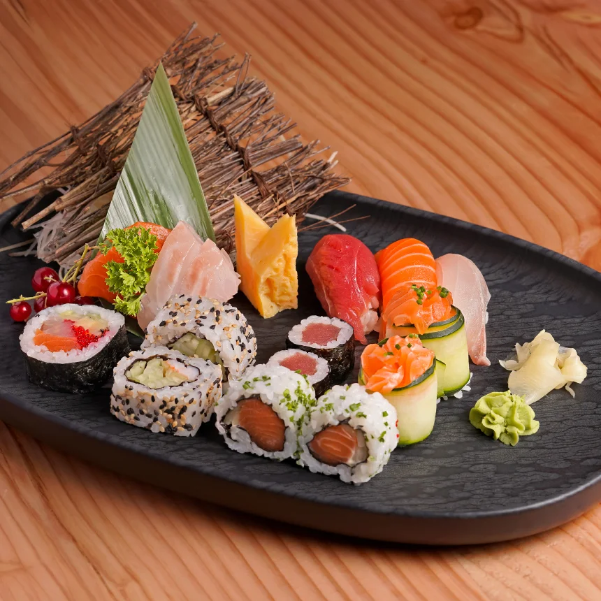 Projeto Izakaya Matsuri da Nhdesign: Fotografia de um elegante prato preto cheio de uma variedade de sushi e outros pratos asiáticos.