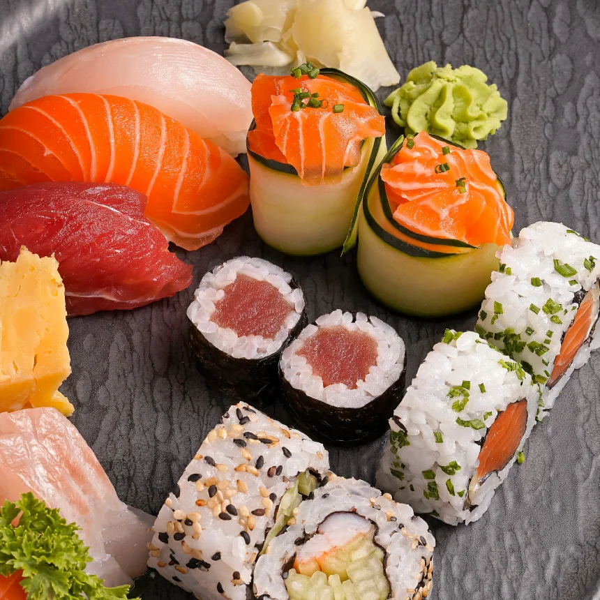 Projeto Izakaya Matsuri da Nhdesign: Fotografia em close-up de um elegante prato preto cheio de uma variedade de sushi e outros pratos asiáticos.