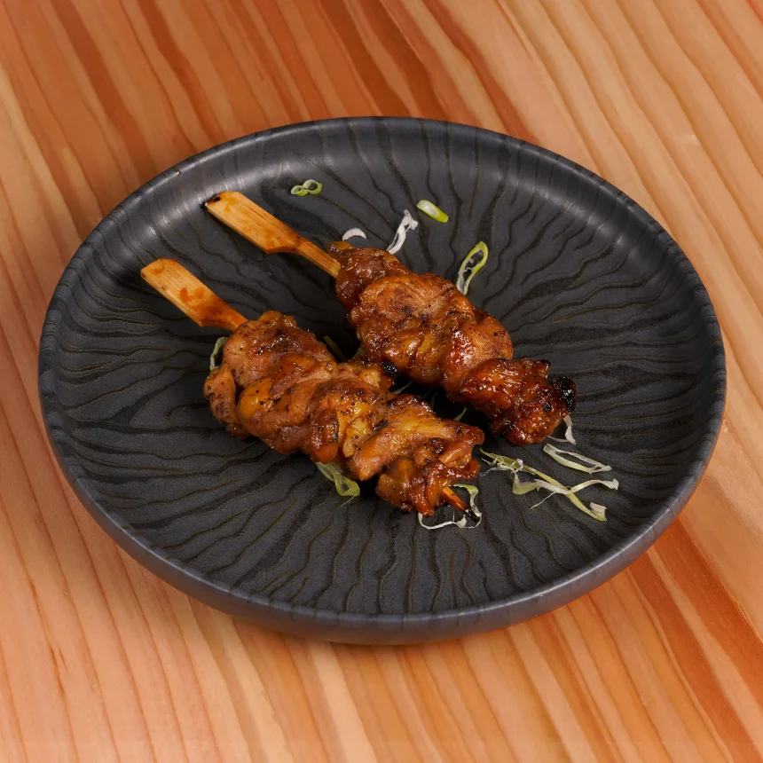 Projeto Izakaya Matsuri da Nhdesign: Dois espetos num prato preto.