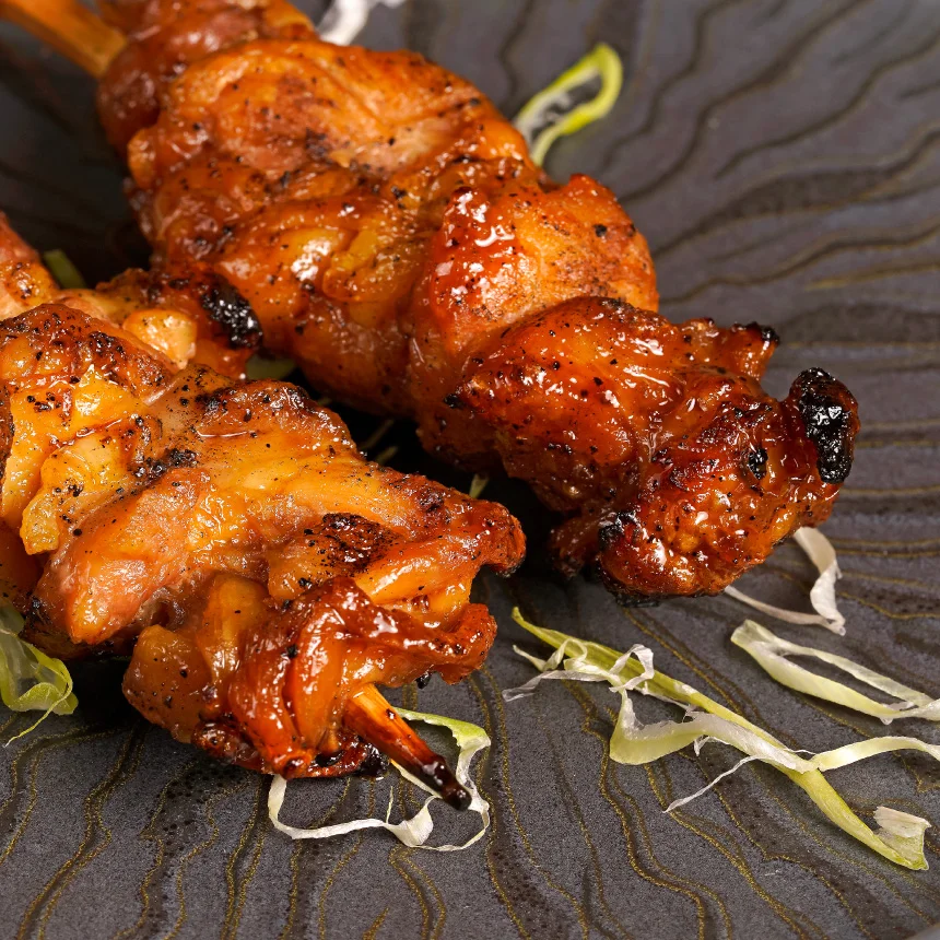 Projeto Izakaya Matsuri da Nhdesign: Fotografia em close-up de dois espetos num prato preto.