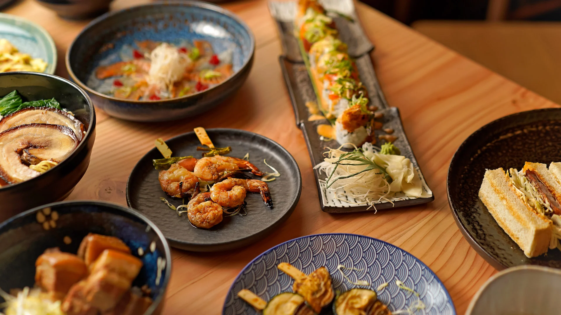 Projeto Izakaya Matsuri da Nhdesign: Uma variedade de pratos japoneses dispostos sobre uma mesa.