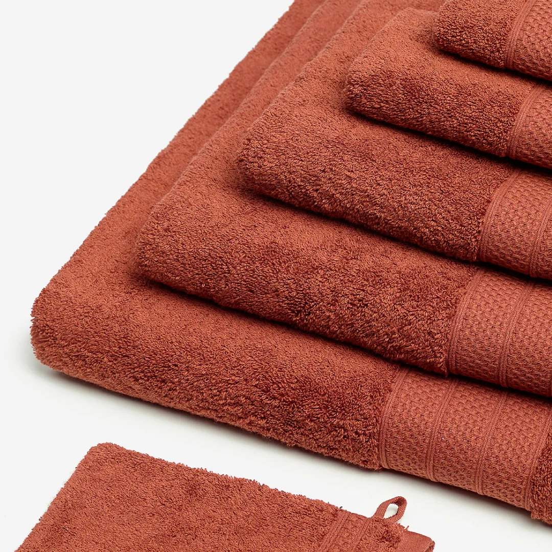 Projeto Kazley da Nhdesign: Conjunto de toalhas Kazley vermelhas dobradas sobre fundo neutro