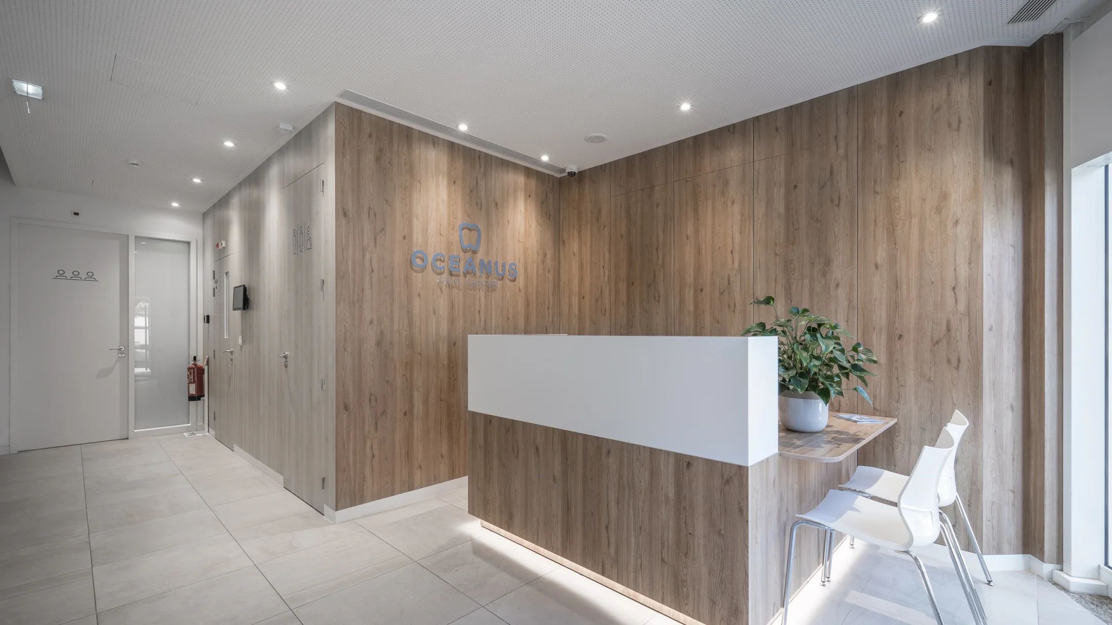 Projeto OCEANUS da Nhdesign: Área de receção da clínica Oceanus Oral Center com balcão em madeira e branco