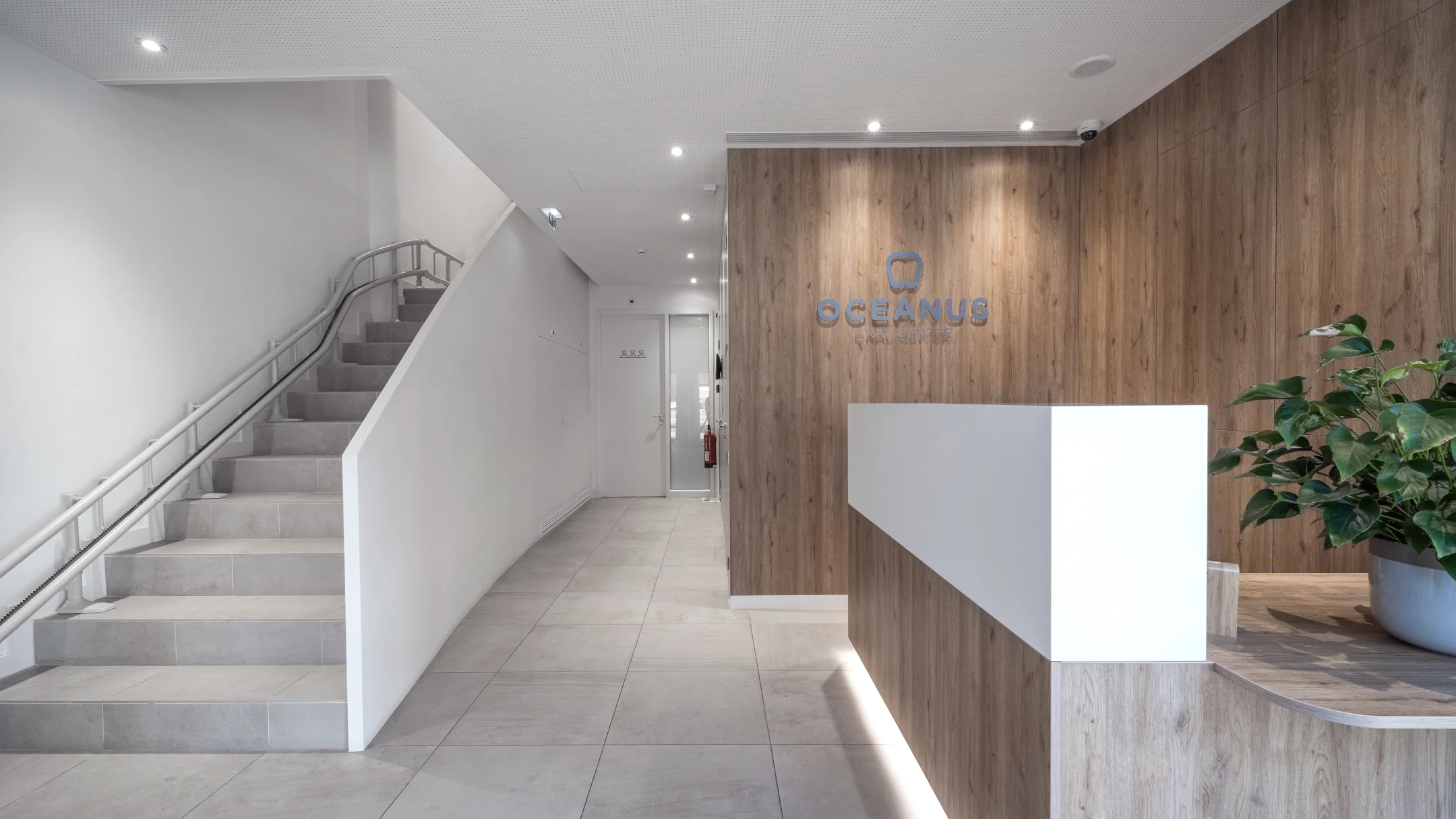 Projeto OCEANUS da Nhdesign: Área da receção Oceanus Oral Center com escadas modernas em madeira e branco