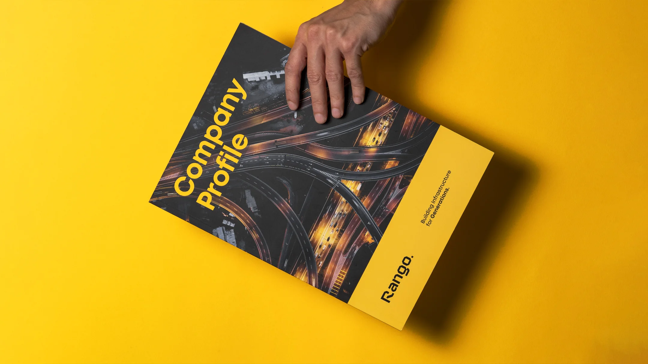 Nhdesign project Rango Company Profile: Company profile held by a hand, on a yellow background.