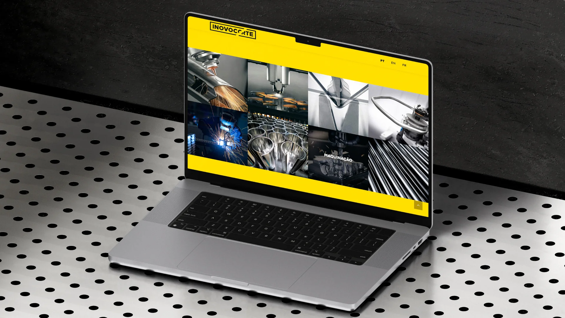 Nhdesign project Inovocorte: A laptop on a perforated metal surface displays industrial machinery images on its screen with a yellow website header